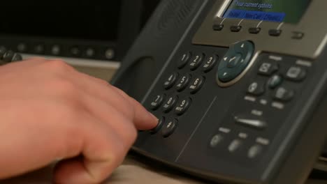 a close up of a hand picking up and dialing an office phone then hanging up in slow motion