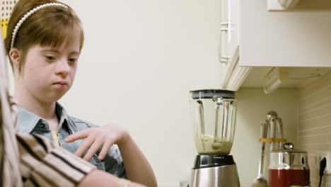 girl with down syndrome putting apple pieces inside a blender