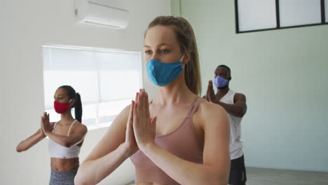 diverse fit people wearing face masks performing yoga in yoga studio