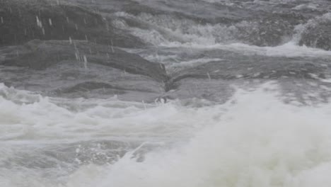 wild turbulent cold water over rocks on nordic river - close up shot