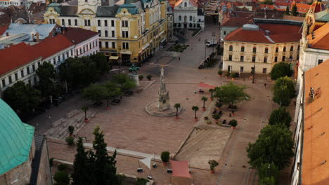 Empty-Szechenyi-Square-In-Pecs-City,-Hungary-With-The-Famous-Statue-Of-Trinity-At-Sunrise