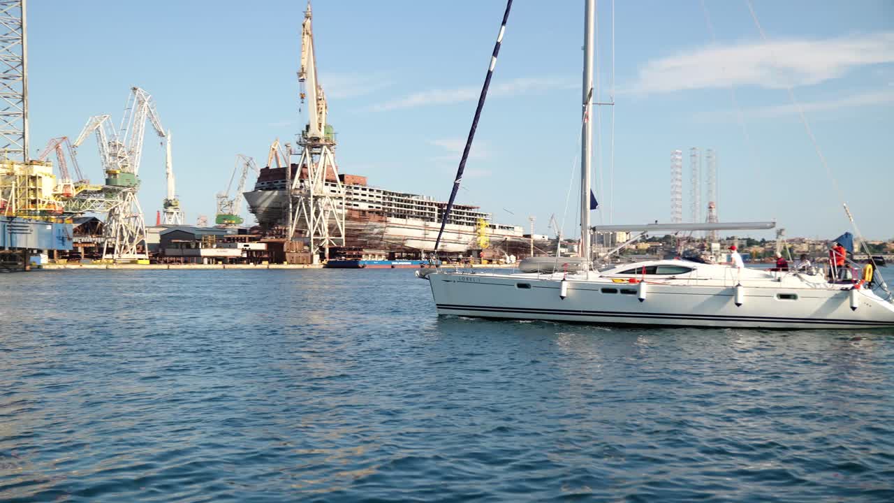Passeggeri ed equipaggio su uno yacht bianco navigano vicino alla piattaforma petrolifera presso il cantiere navale Uljanik a Pola.