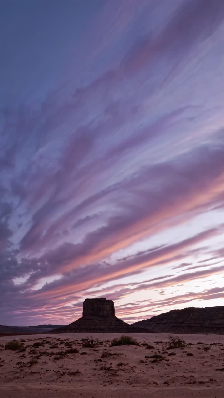 A wide-angle video captures a dramatic desert sunset with vibrant clouds and a silhouetted rock