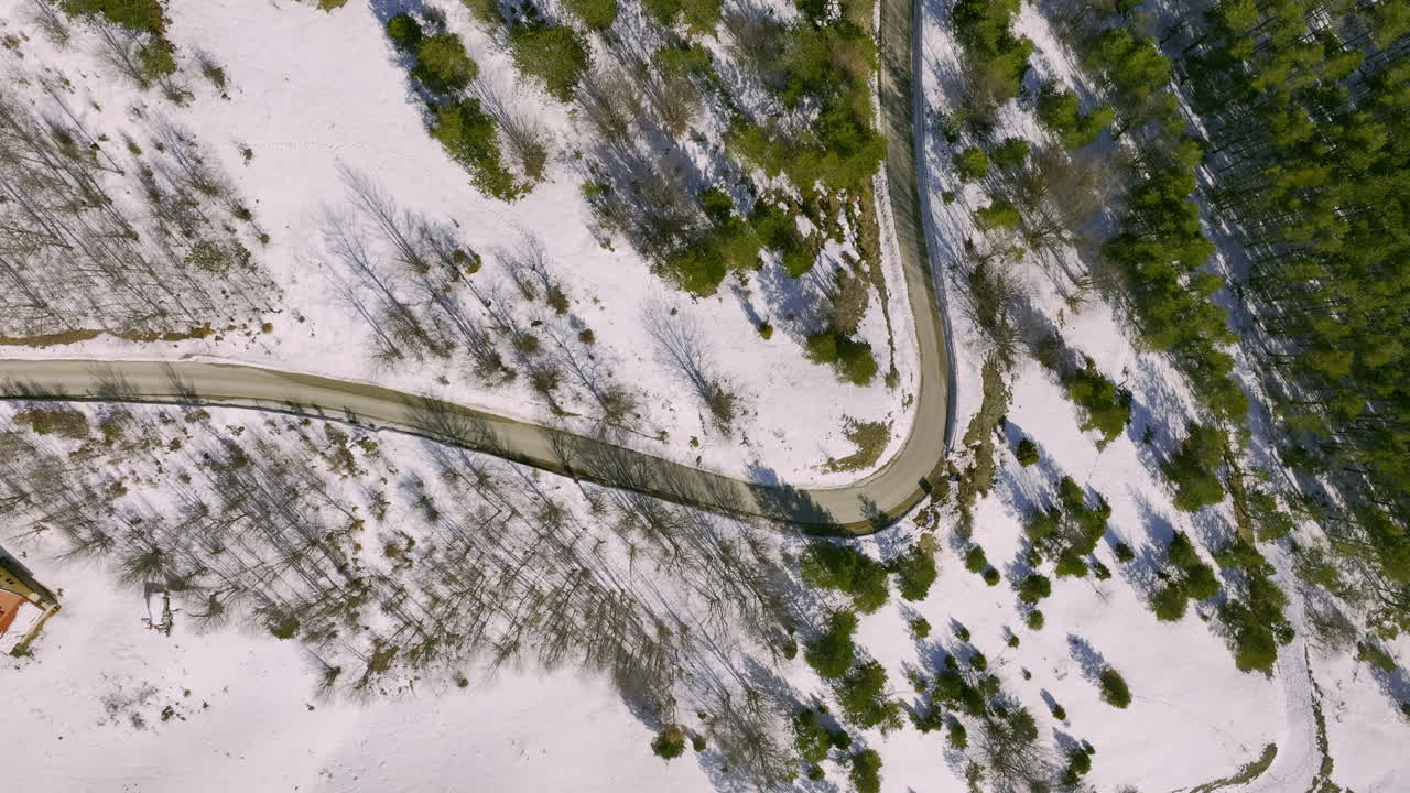Aerial View of Winding Road Through Snow-Covered Forest in Winter