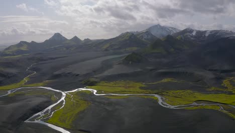 un video de drones en cámara lenta de las tierras altas del sur de islandia que muestra arenas negras, musgo verde y nieve en las montañas