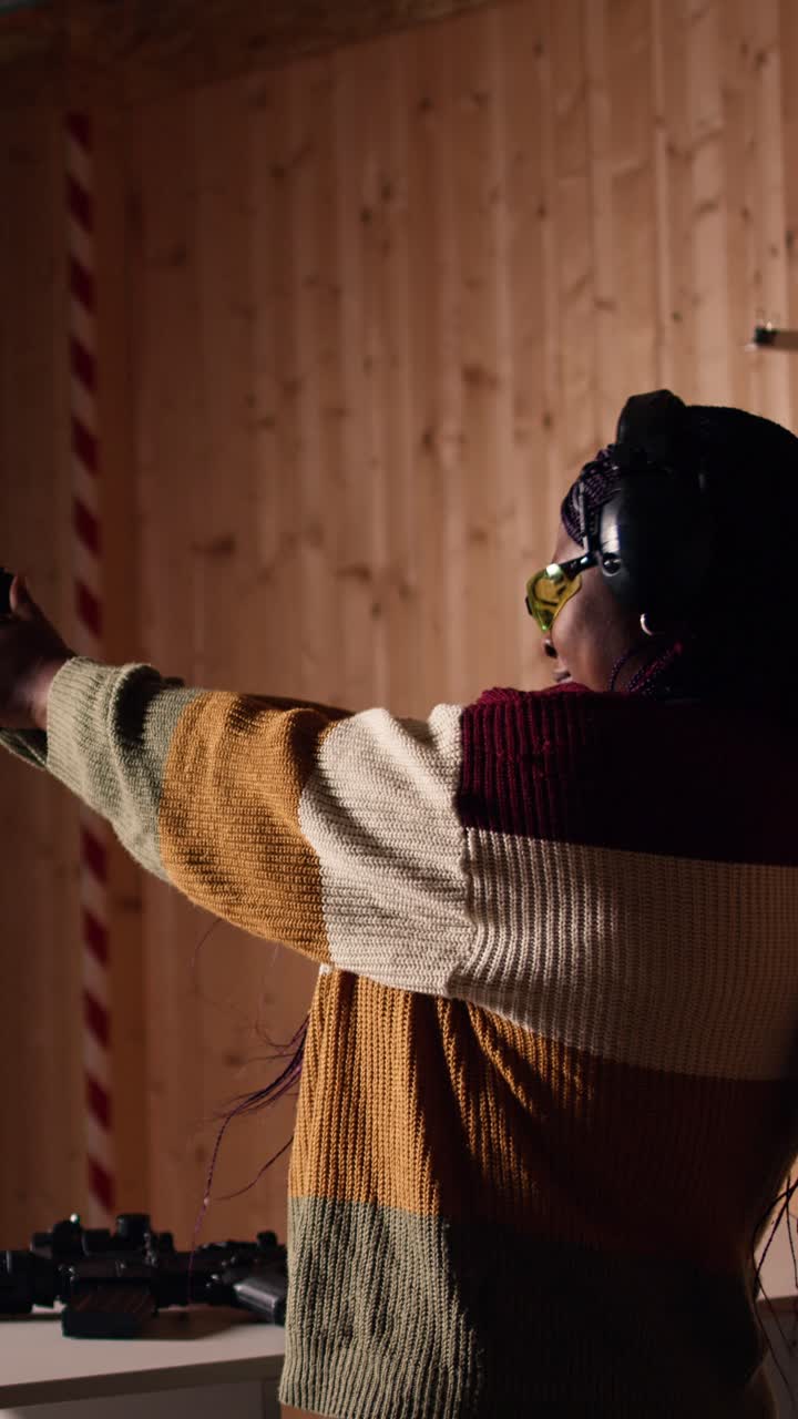 Vertical video Cheerful woman in shooting range trying out new gun model