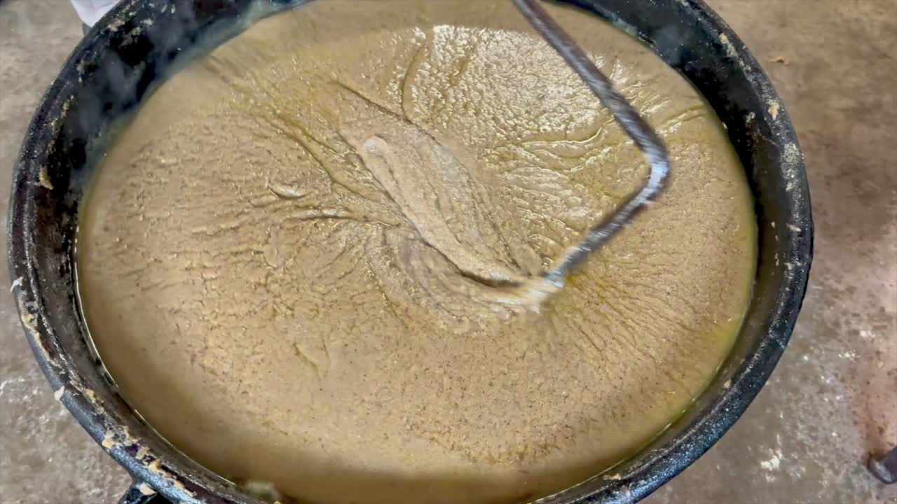 Traditional scrapple being stirred in a large cast iron kettle over heat
