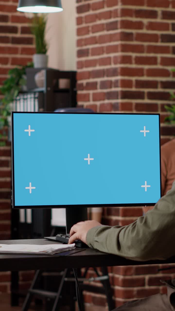 Person working on a computer with a green screen in an office