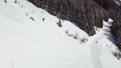 Aerial-drone-shot-of-snowy-landscape,-pathway-in-skiing-area-of-Kleinwalsertal-in-the-alps,-Austria