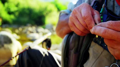 pescador con mosca preparando cebo para la pesca