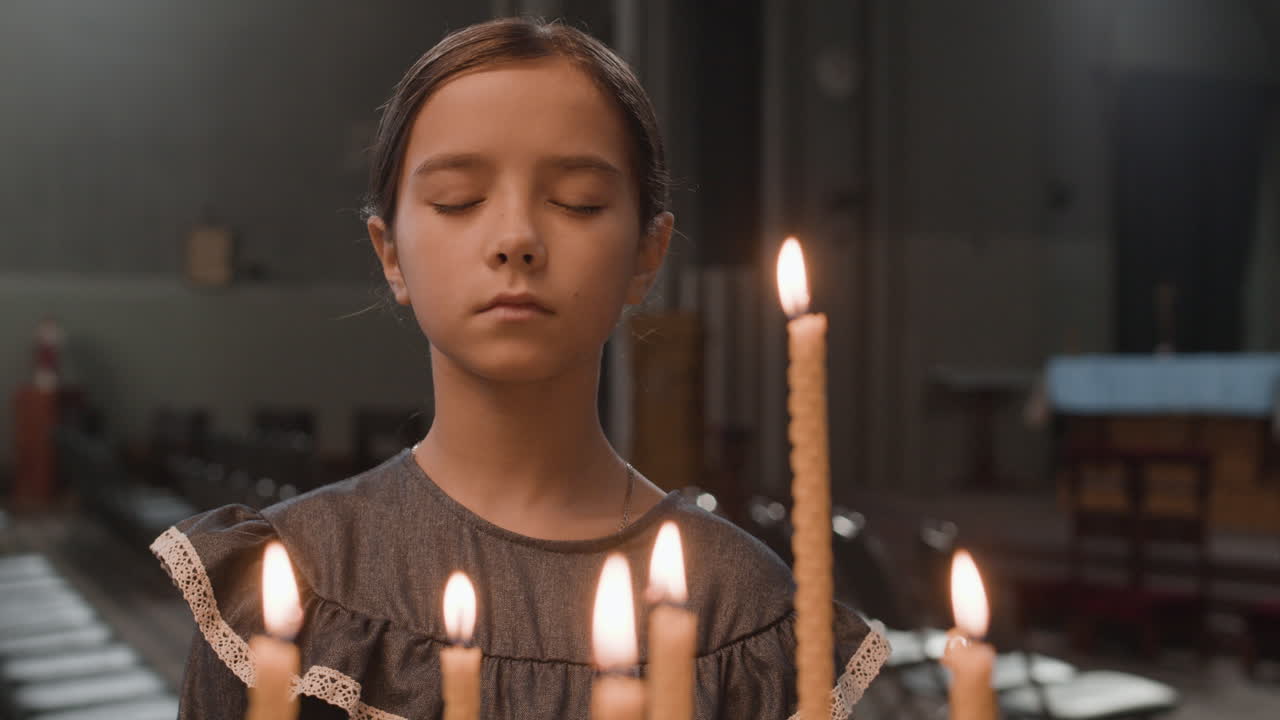 Girl praying in church with candles