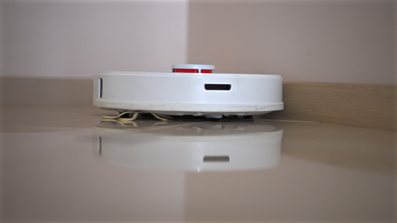 Futuristic white and orange robot vacuum cleaner sweeping the floor