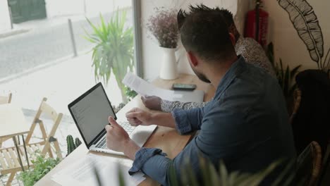 Freiberufler-Arbeiten-Mit-Laptop-Und-Papieren-Im-Café