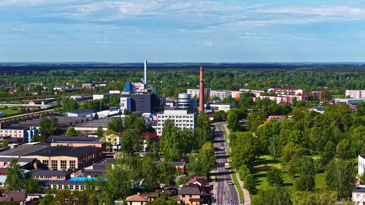 Small industrial town with chimneys and green trees on a sunny summer day