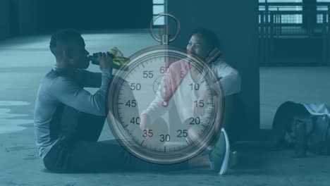 stopwatch against african american man and woman taking a break from working out