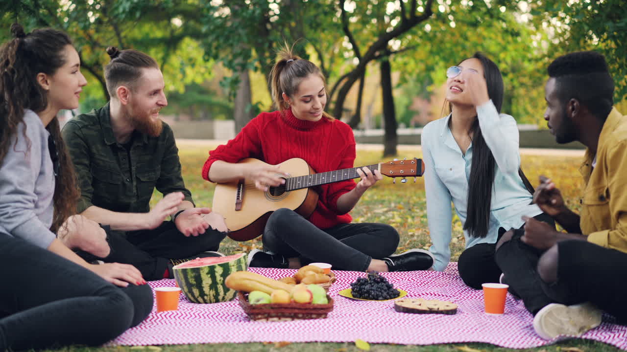 Friends enjoying a picnic and playing guitar in a park