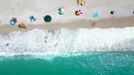 people relaxing and playing in the shore of a beautiful beach overhead shot