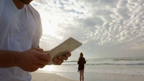 vista de bajo ángulo de un joven caucásico usando una tableta digital en la playa en un día soleado 4k