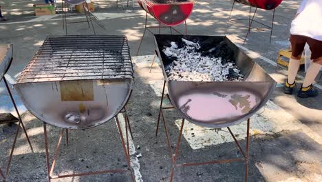 people preparing the coals for cooking sardines at cascais market during santos populares in lisbon, portugal