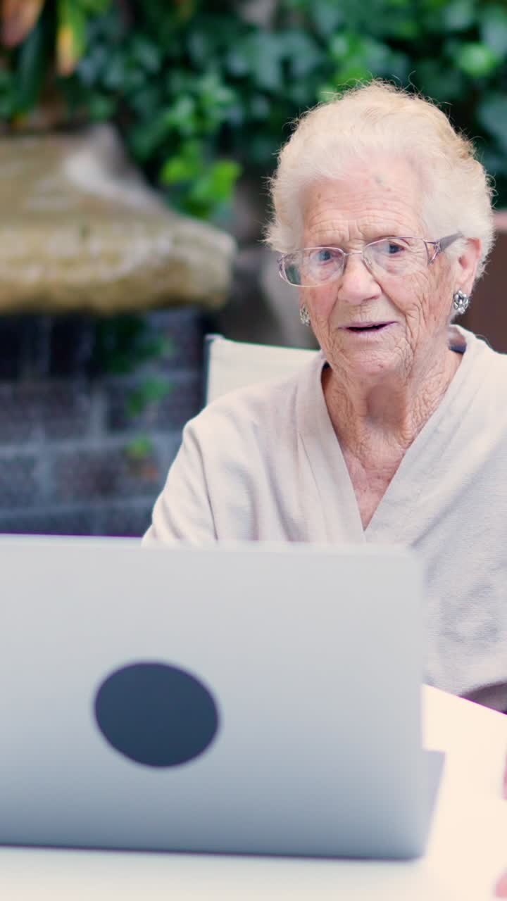Elderly woman using a laptop in the garden