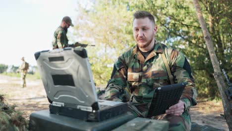 un comandante del ejército experimentado y serio está en el campo teniendo una conversación de video en la computadora con el jefe de la base del ejército, dándole detalles de la acción discutiendo las precauciones tomadas, información secreta