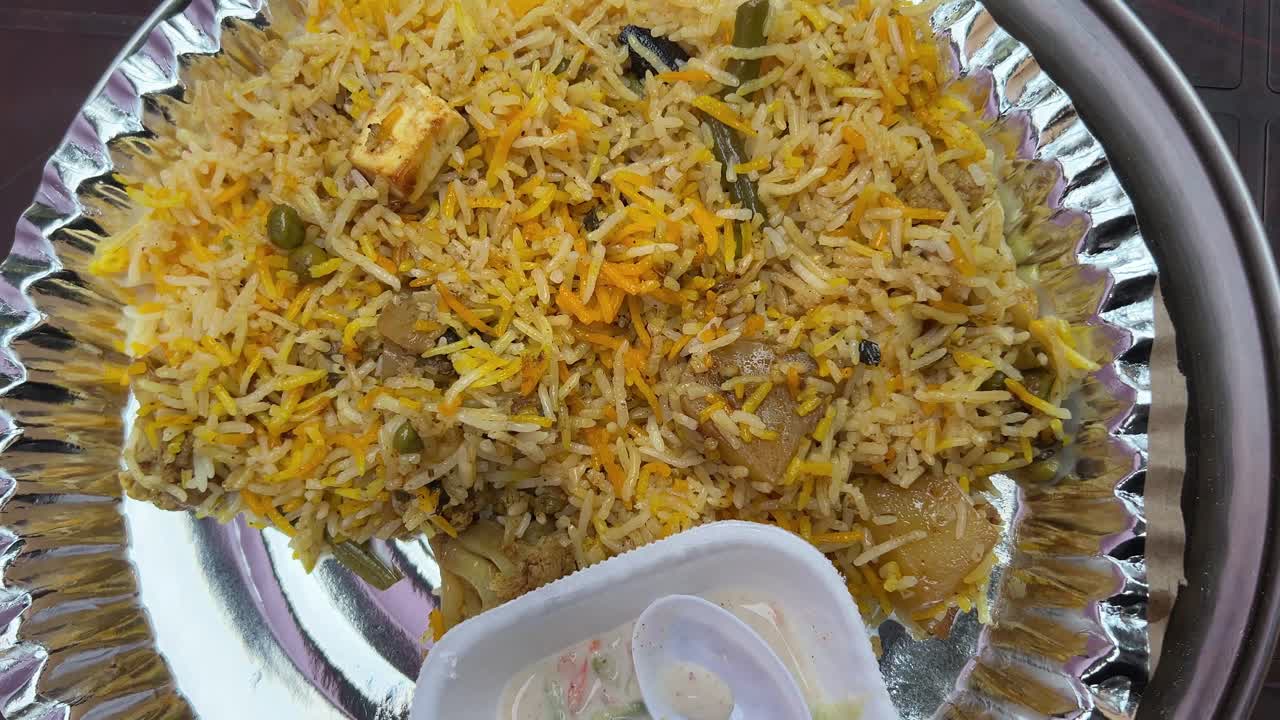 biryani vegano con cubos de paneer y servido con raita.