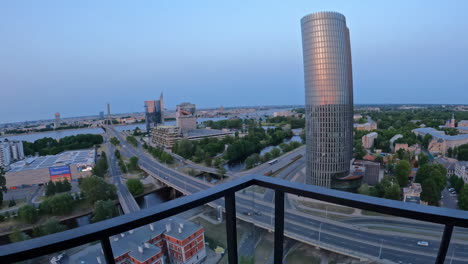 Push-in-between-railing-and-ceiling-reveals-road-and-town-at-blue-hour,-Riga-Latvia