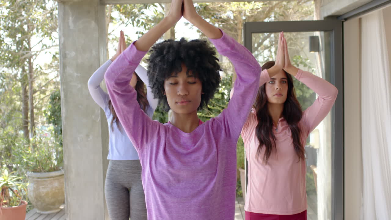 Mulheres praticando yoga juntas em casa, focando em mindfulness e relaxamento.