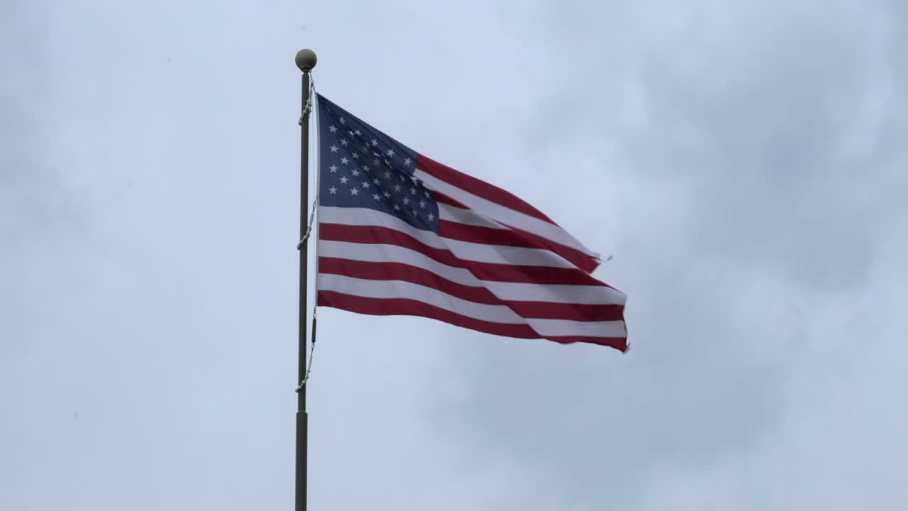 bandera estadounidense ondeando en el viento con nubes de tormenta en el fondo