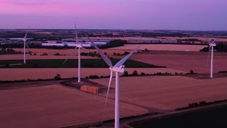 aerial moving down wind turbines farm during blue hour, pink sunset over fields in langford, biggleswade, bedfordshire, england, uk