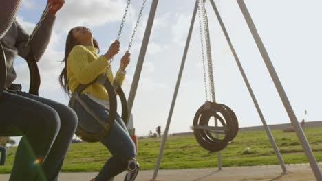 happy couple playing on playground swing in the park 4k