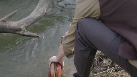 cowboy filling up his canteen in a river