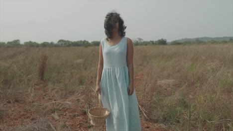 wide shot of a woman in a blue dress with the basket in the hand in a wide field