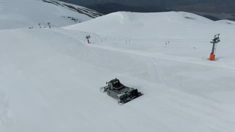 snow groomer grooming ski slopes on snow covered mountains