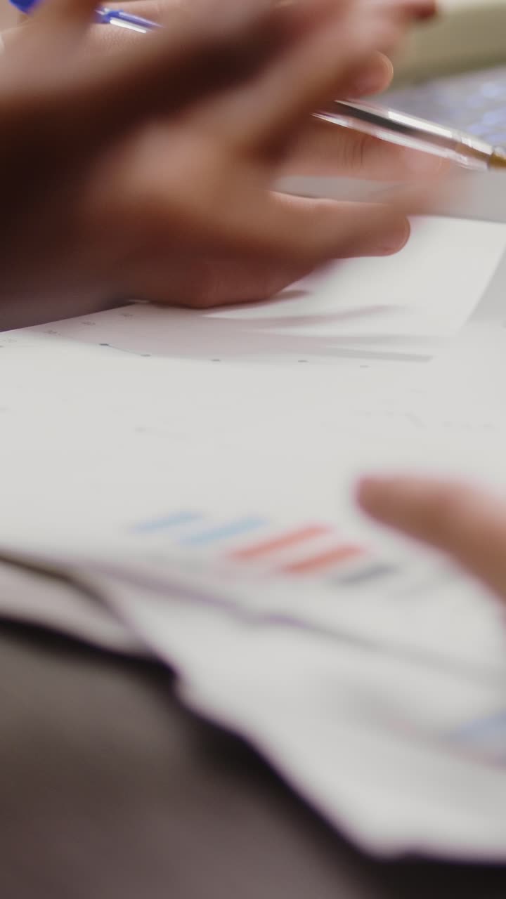 Vertical video: Diverse women analyzing data statistics on documents