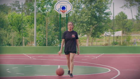 girl practices basketball in outdoor cort long shot