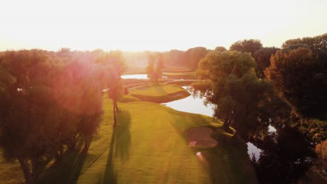 aerial, landspace drone shot above golf course flying down during sunny sunset in warsaw, poland