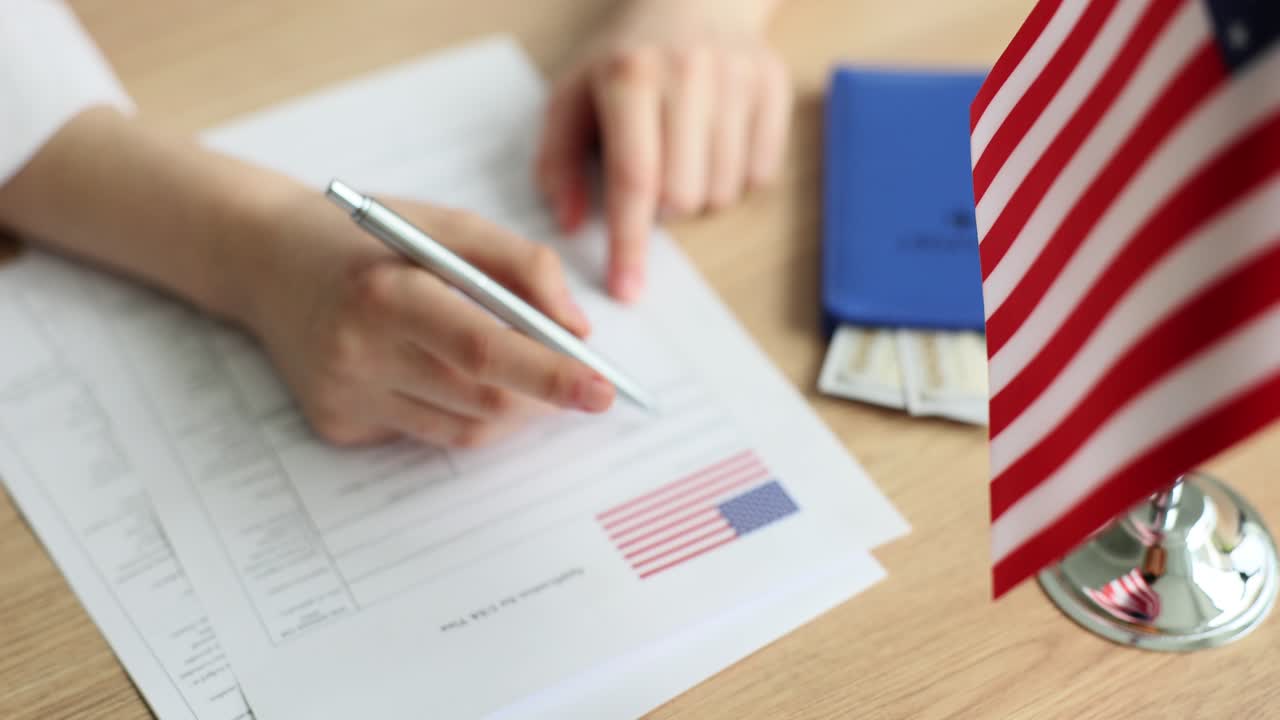 Woman fills in visa application form near american flag