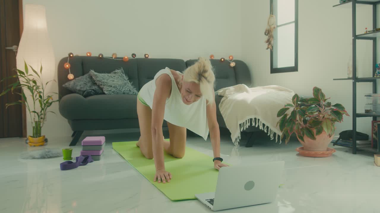 mujer practicando yoga en casa a través de clases en línea