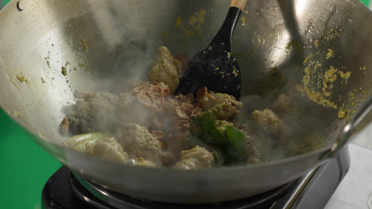 Golden chicken cooked in a wok with turmeric and fried garlic