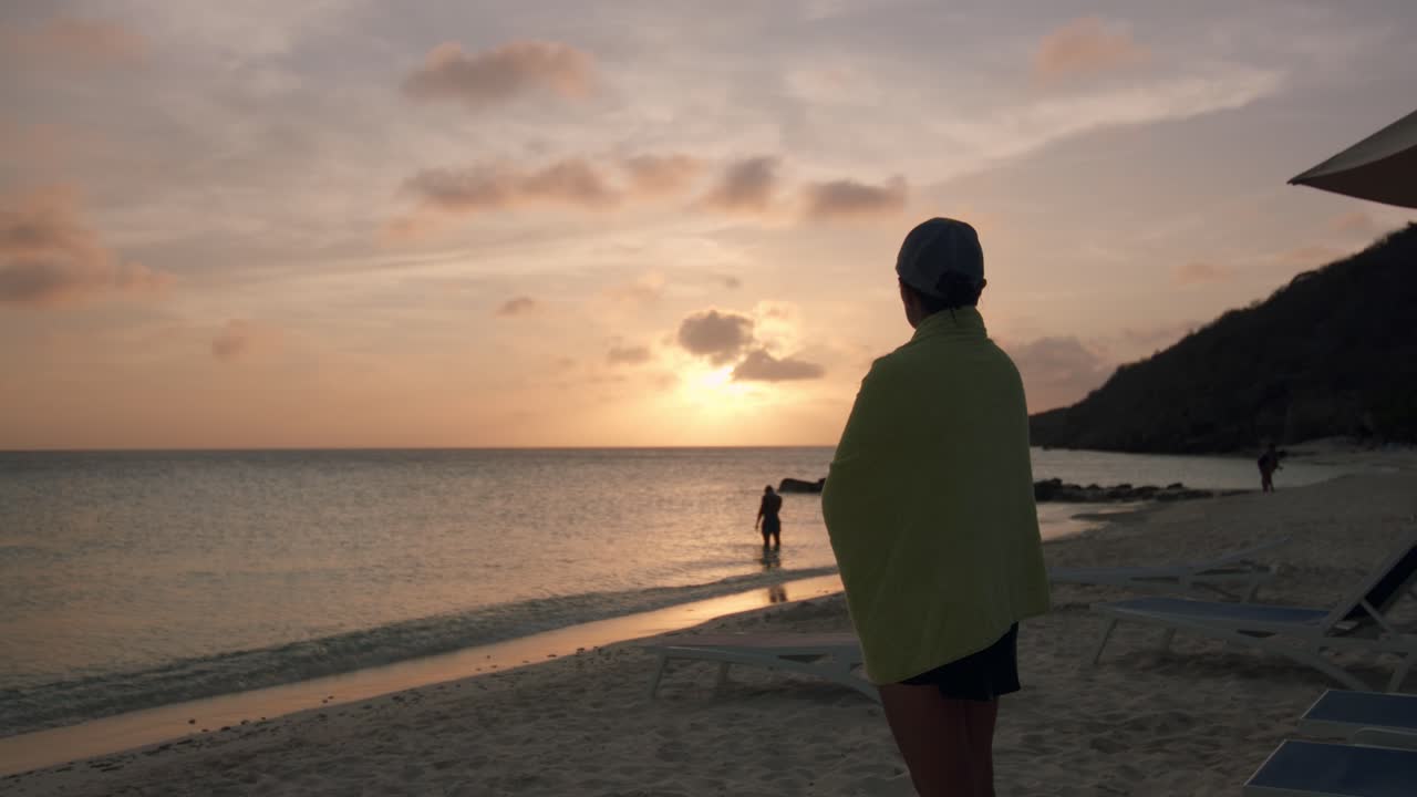쿠라사오 의 카리브 해 위 에 해 가 지는 동안 모래 해변 에 서 있는 여자