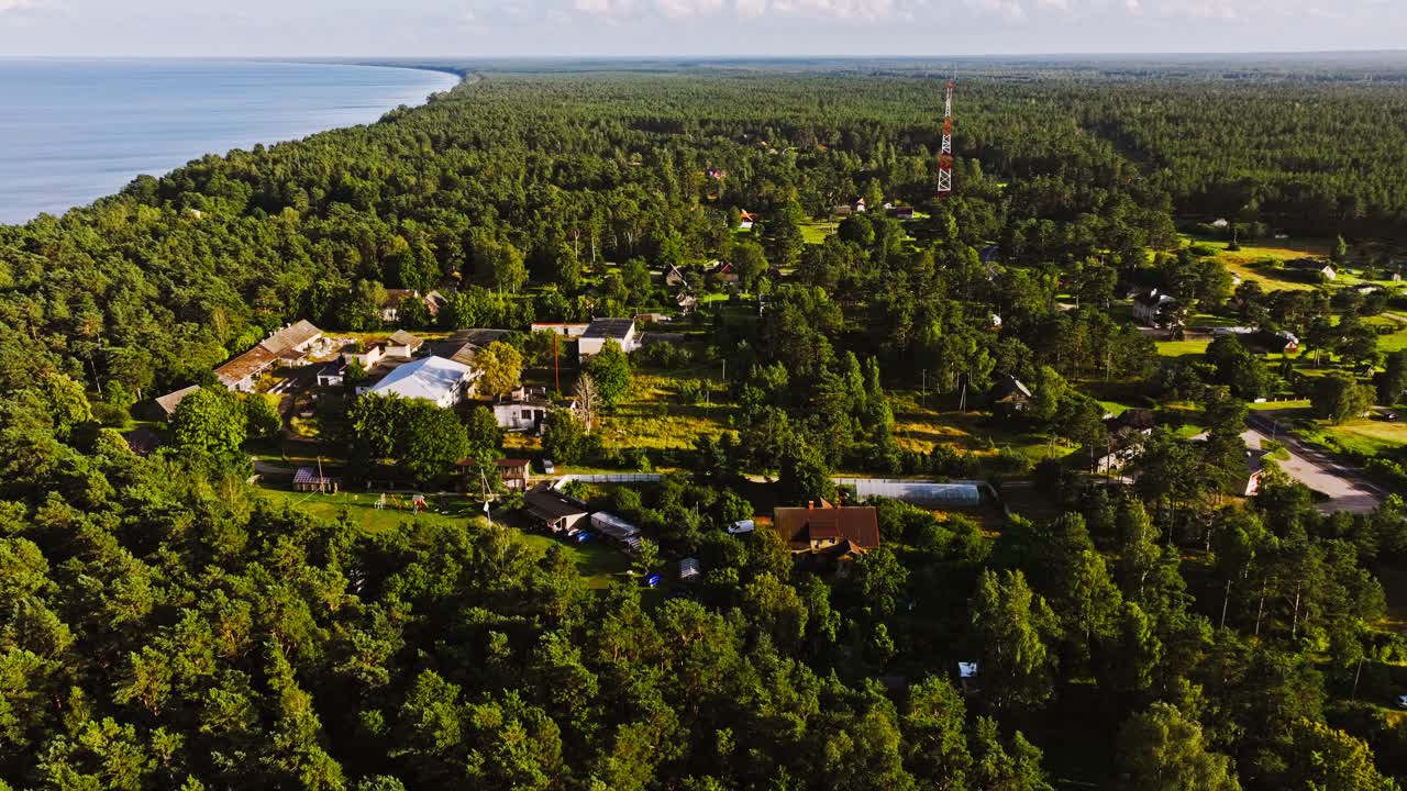 Aerial sunset over Melnsils Latvia, coastal forest and seaside rural community