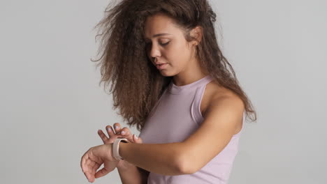 una mujer caucásica de cabello rizado revisando las notificaciones en su reloj inteligente.