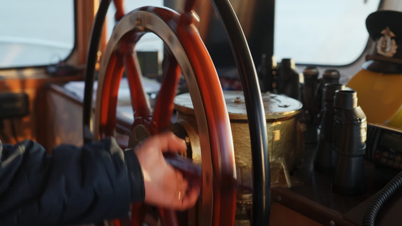 A person's hand on a classic ship's wooden steering wheel