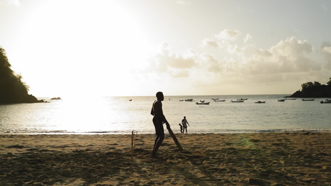 Young man playing cricket on the beach in Tobago