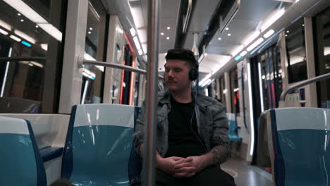 a male traveler with a headset and the few others inside the train of montreal metro in underground city in canada - coronavirus pandemic - medium closeup shot pan right