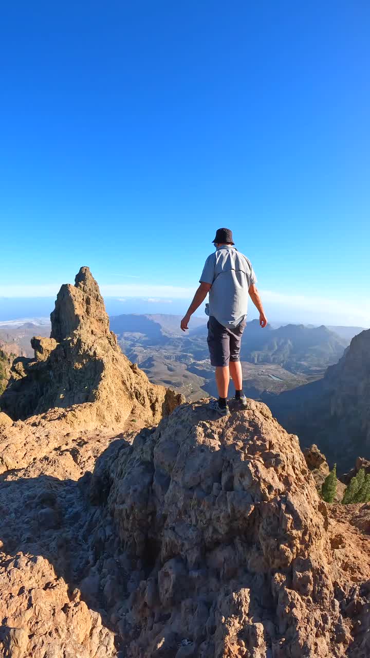 Uomo in piedi sulla cima di una montagna che guarda un paesaggio panoramico