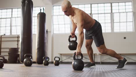 fit caucasian man working out with kettle bells at the gym