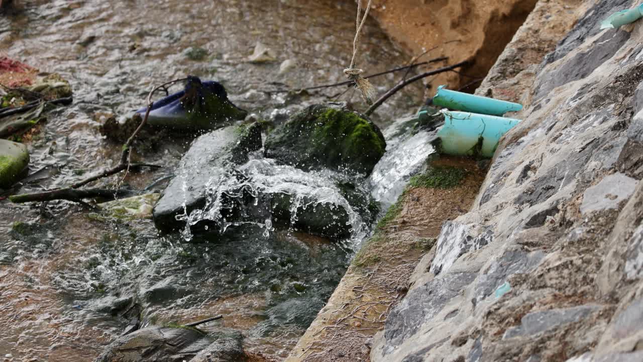 Water flows through a concrete drainage channel, highlighting urban stormwater management and pollution issues