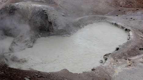 Primordial-looking-boiling-hot-geothermal-water-with-steam-rising-from-a-hot-spring-in-Yellowstone-National-Park